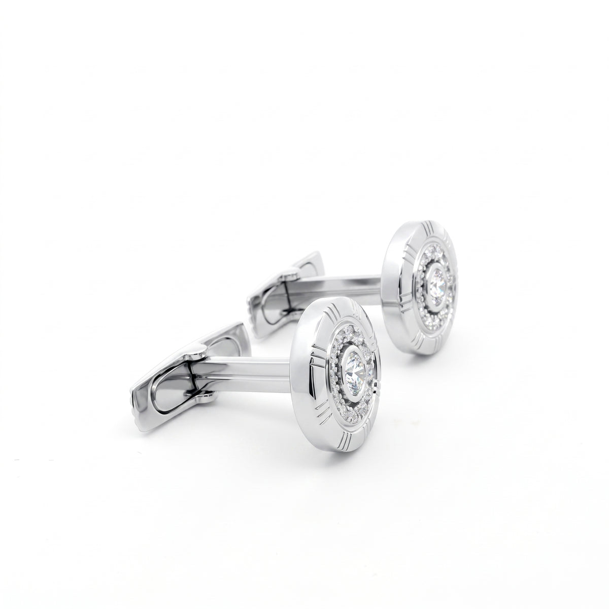 A pair of silver-toned round cufflinks with engraved outer rings and a clear central gemstone, displayed on a clean white background.
