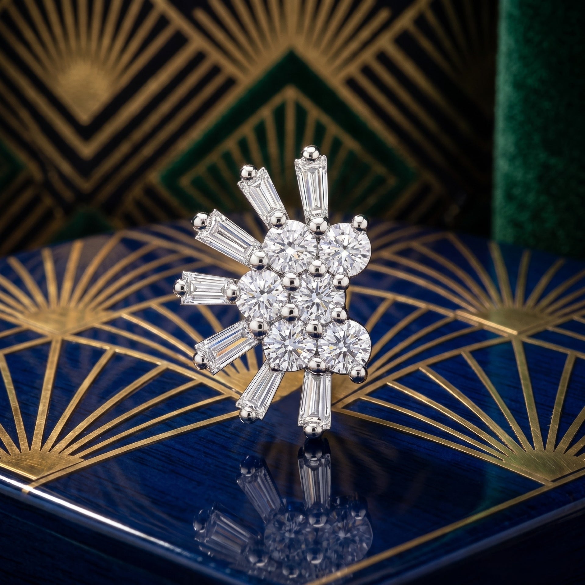 A sparkling Art Deco style nose pin featuring a cluster of round brilliant-cut diamonds surrounded by baguette-cut diamonds in a silver-toned setting, displayed on a blue and gold patterned box.