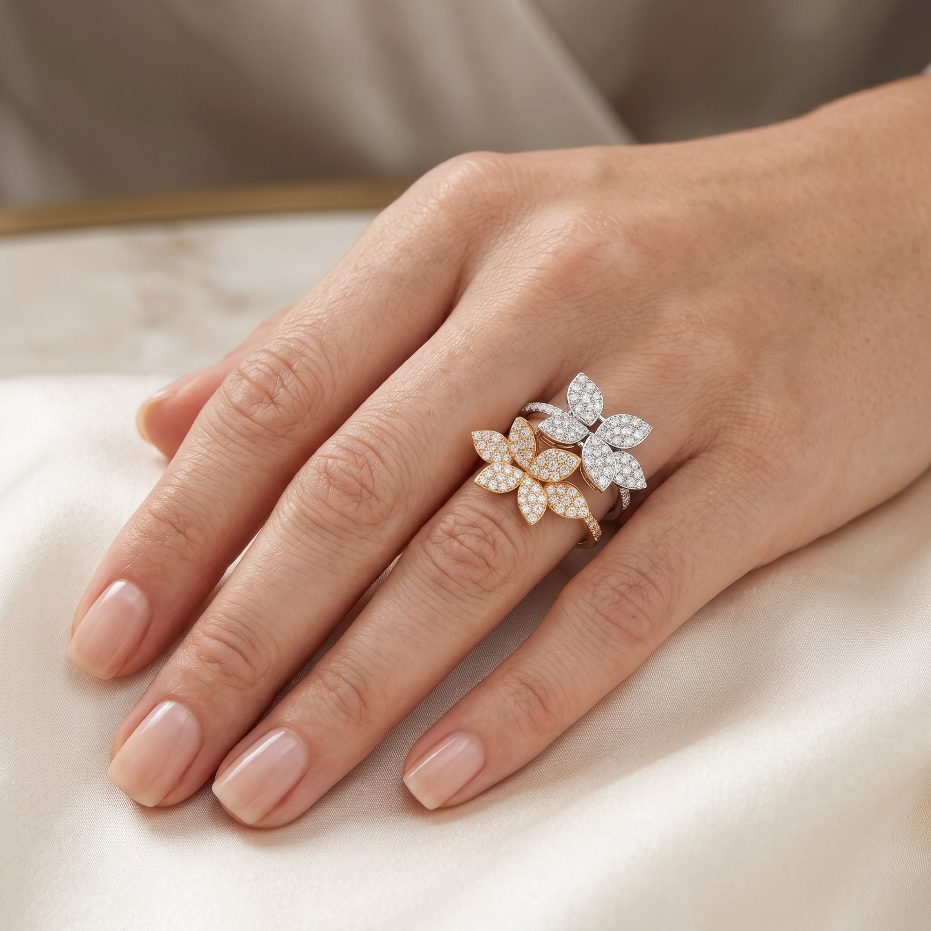 Hand wearing a decorative floral ring on a neutral background