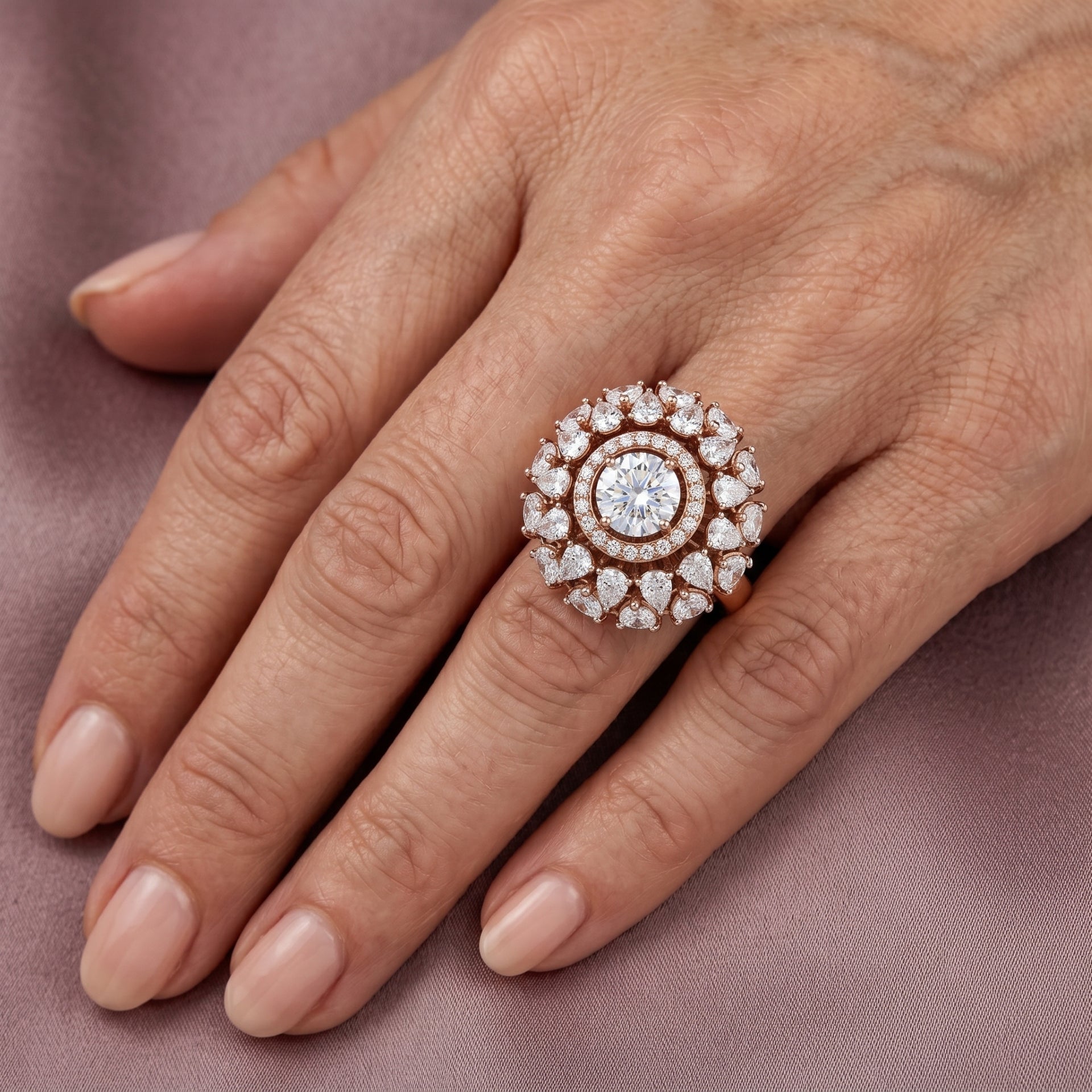 Close-up of a hand wearing a diamond ring on a pink fabric background
