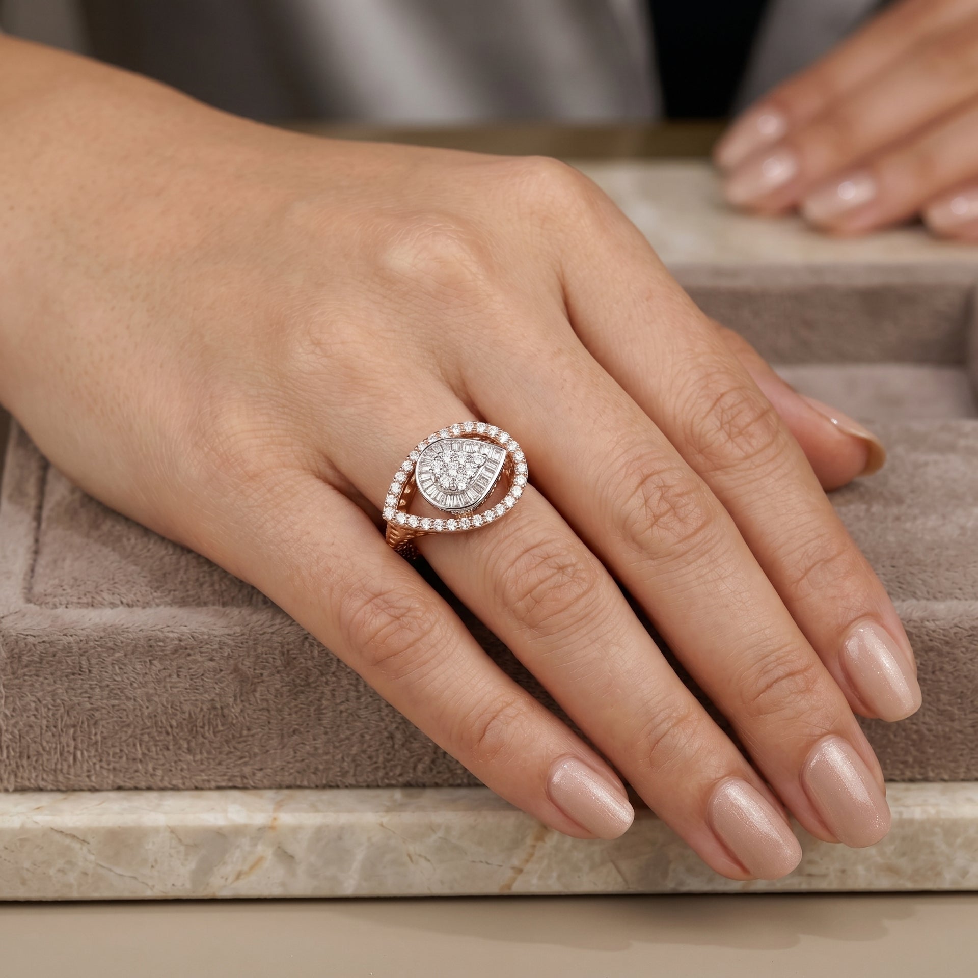 Hand wearing a diamond ring on a neutral background