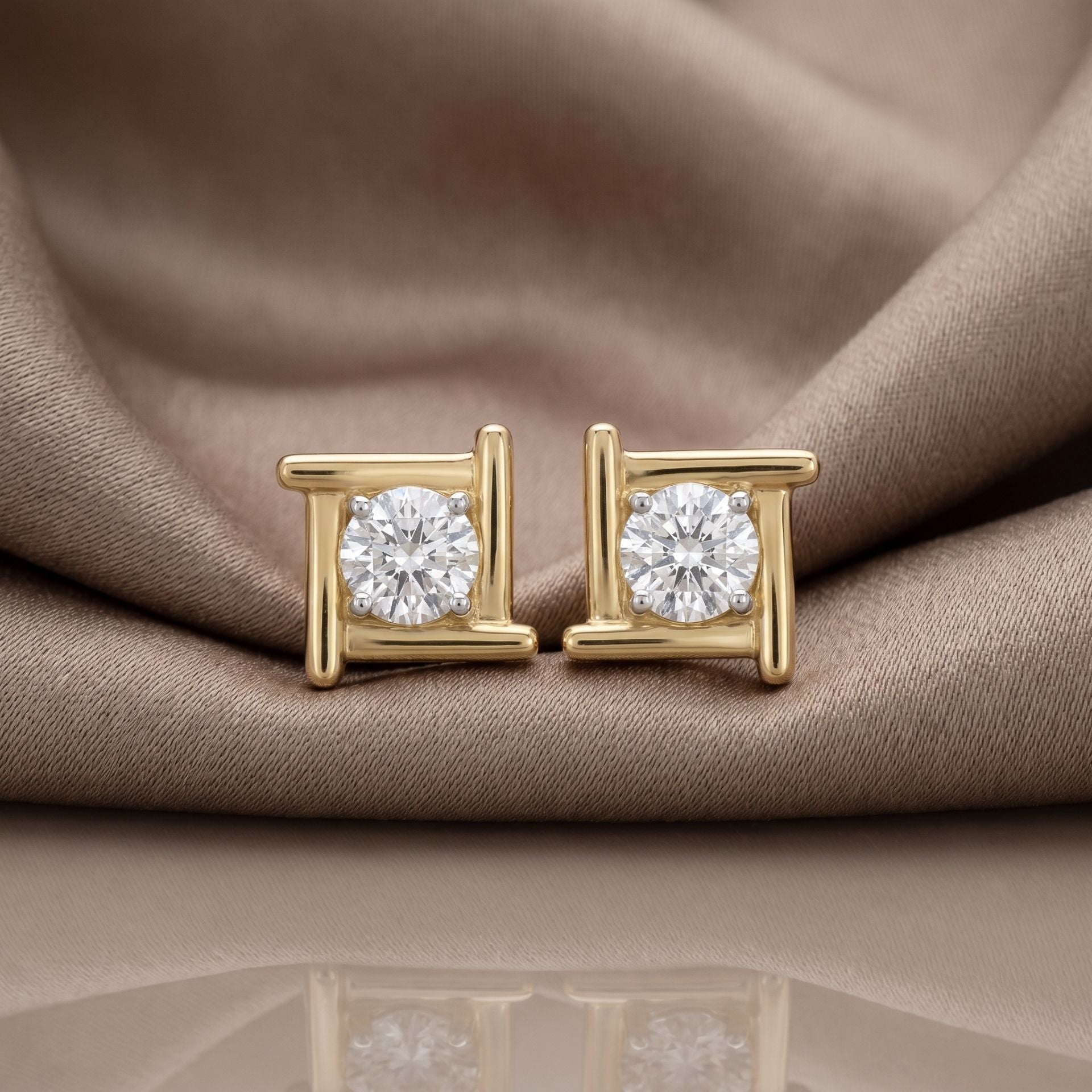 Gold halo lab grown diamond stud earrings on a beige satin background