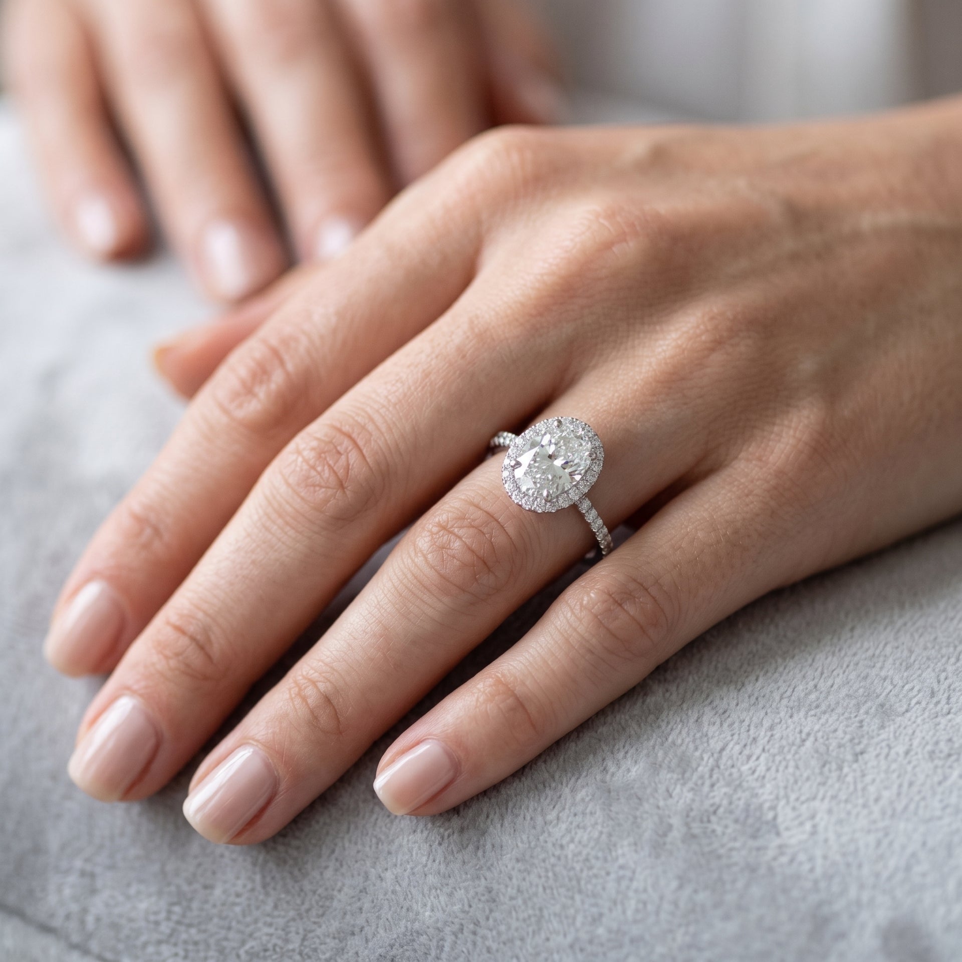 Close-up of a hand wearing a diamond ring on a neutral background