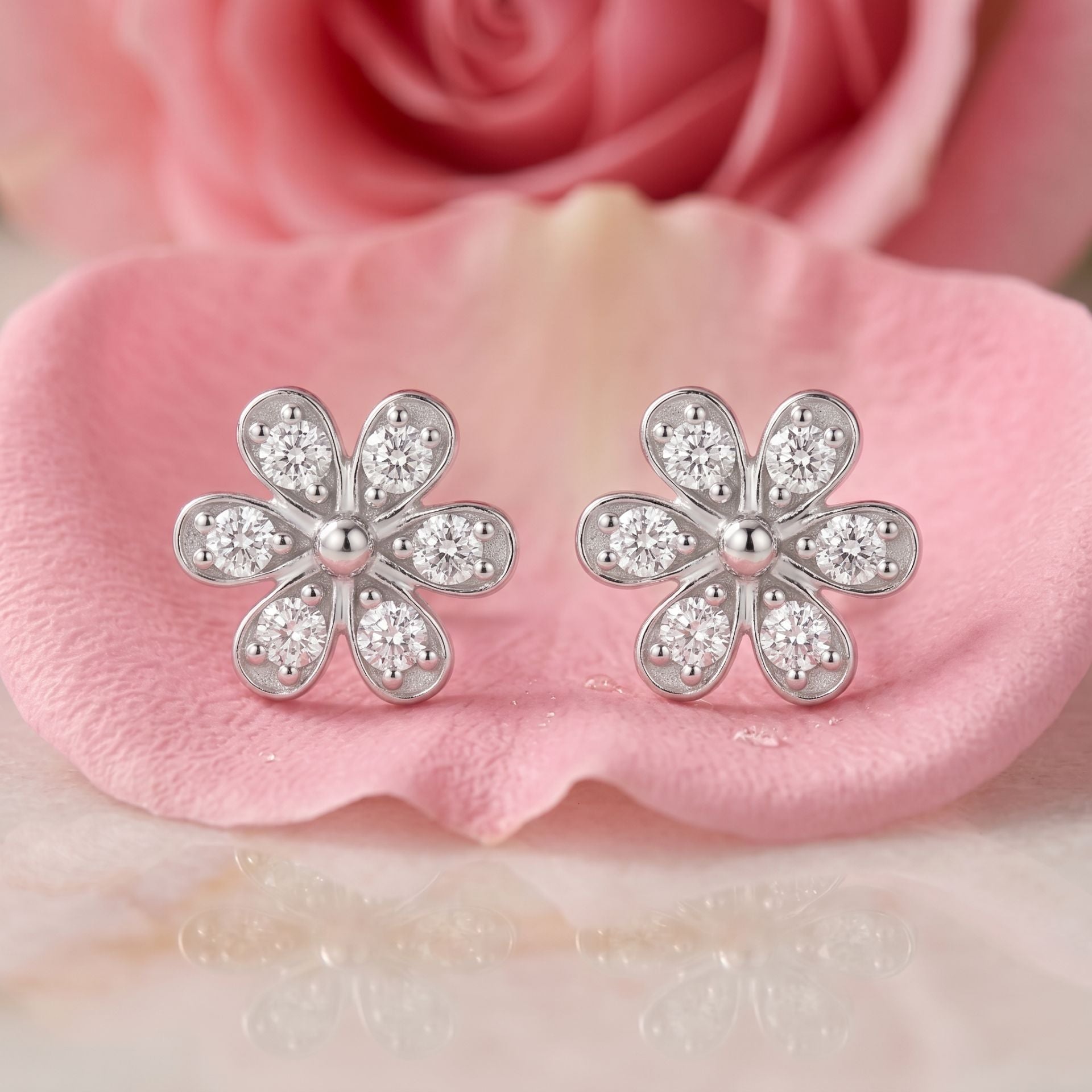Flower-shaped lab grown diamond stud earrings on a pink satin background