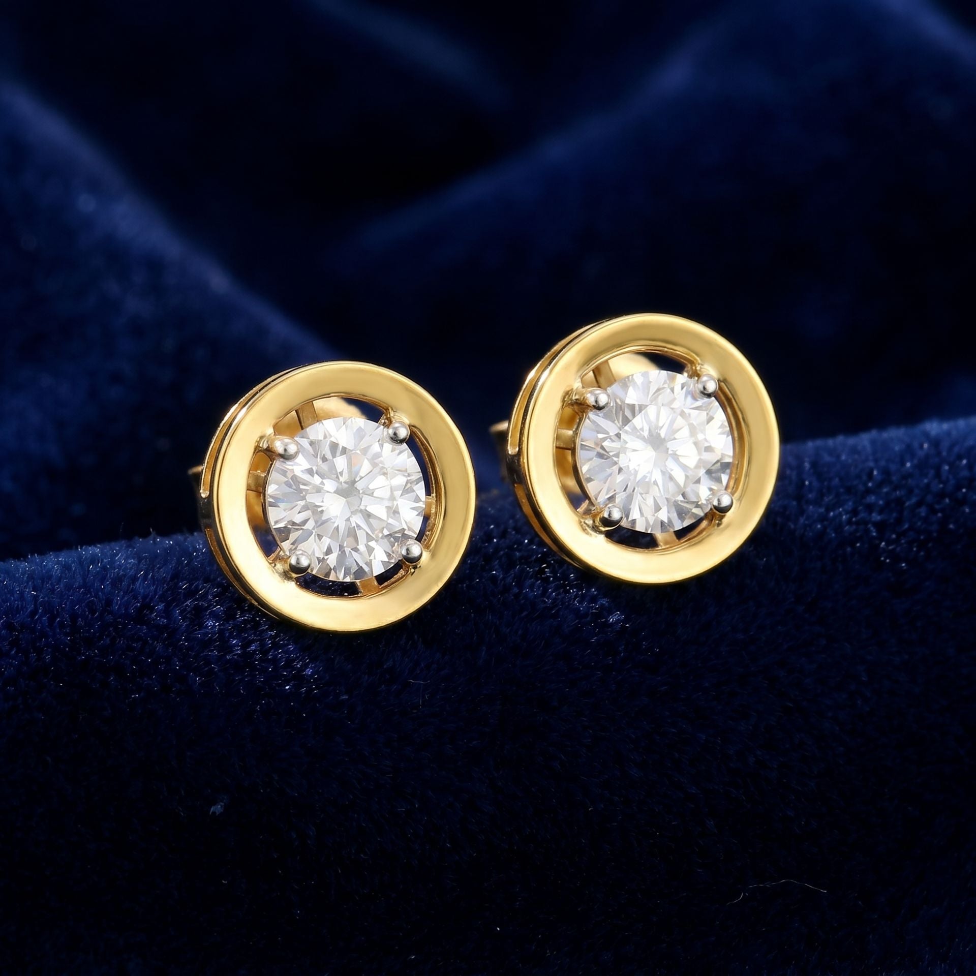 Gold lab grown diamond stud earrings on a dark blue velvet background