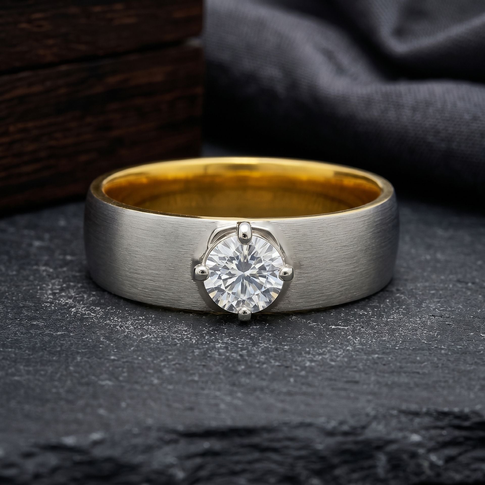 Classic brushed metal ring featuring a round solitaire lab-grown diamond in a secure prong setting on a dark textured surface.