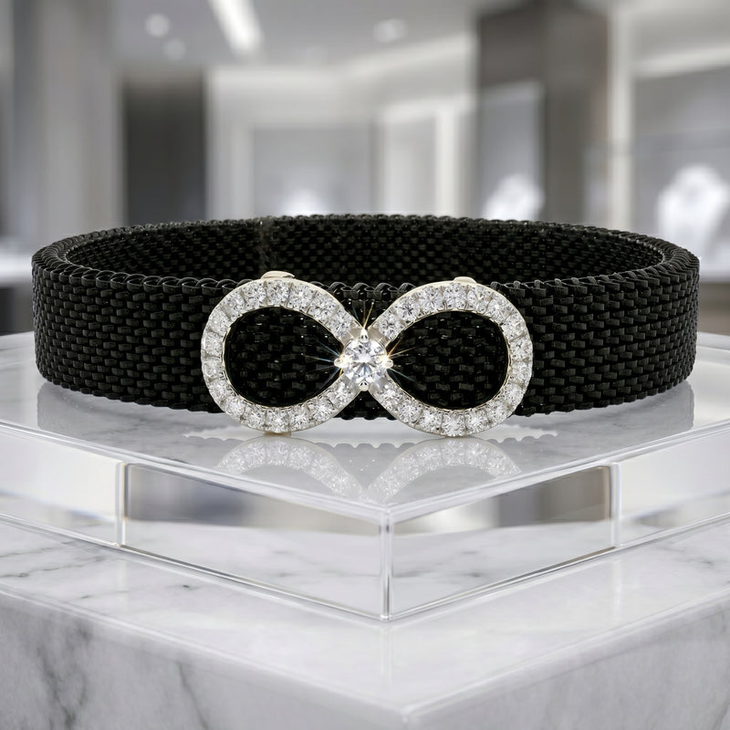 Black belt with a silver, diamond-studded buckle on a reflective surface.