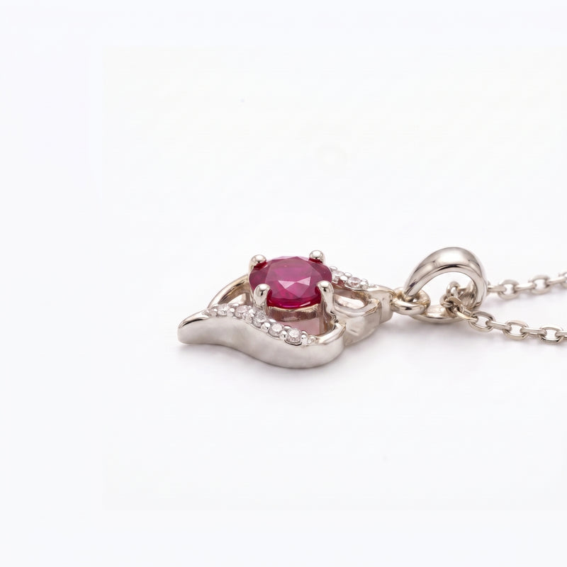 A silver pendant necklace featuring a central oval-cut pinkish-red gemstone surrounded by small clear stones, set on a silver leaf-like crescent design with a matching silver chain, shown on a plain white background.