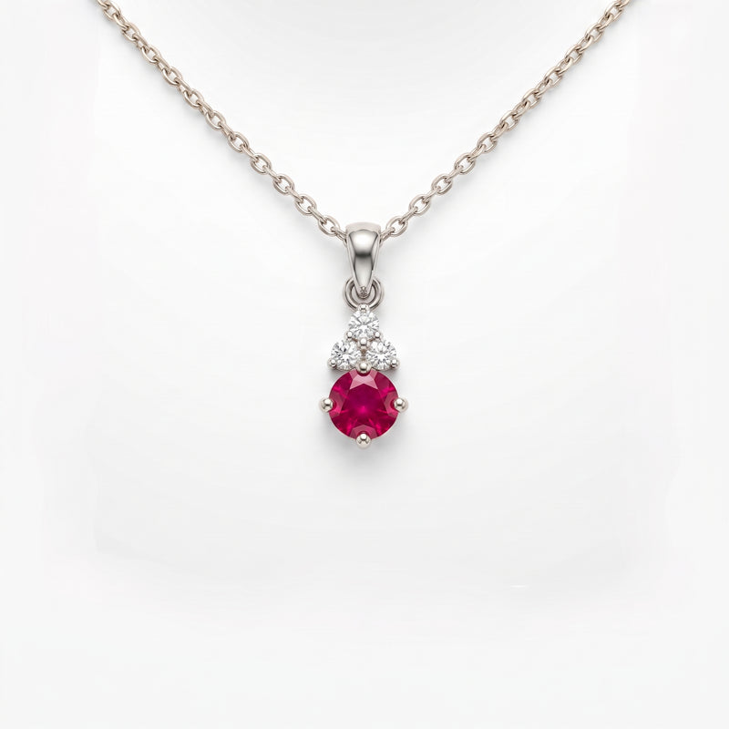 A silver pendant necklace featuring a round pinkish-red ruby gemstone and small clear stones, displayed on a white background.