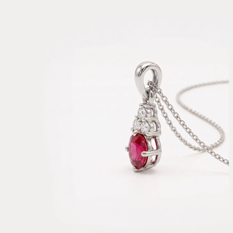 A silver pendant necklace featuring a marquise-cut pinkish-red ruby gemstone and small clear accent stones, shown on a white background with a silver chain.