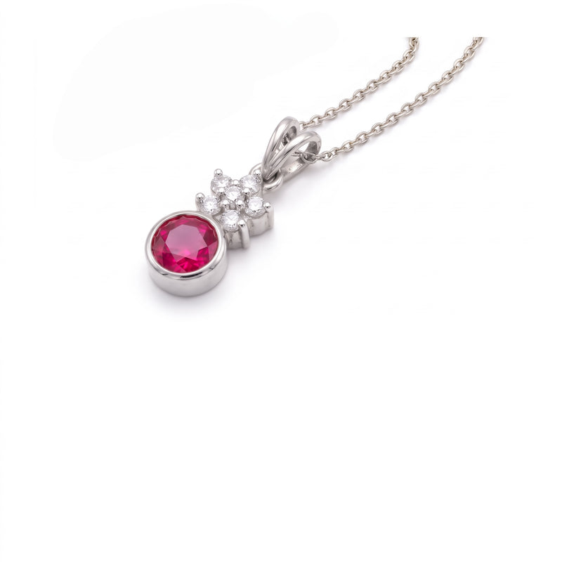 A silver pendant necklace featuring a round pinkish-red gemstone in a bezel setting, with a small cluster of clear stones above it, on a delicate silver chain against a white background.