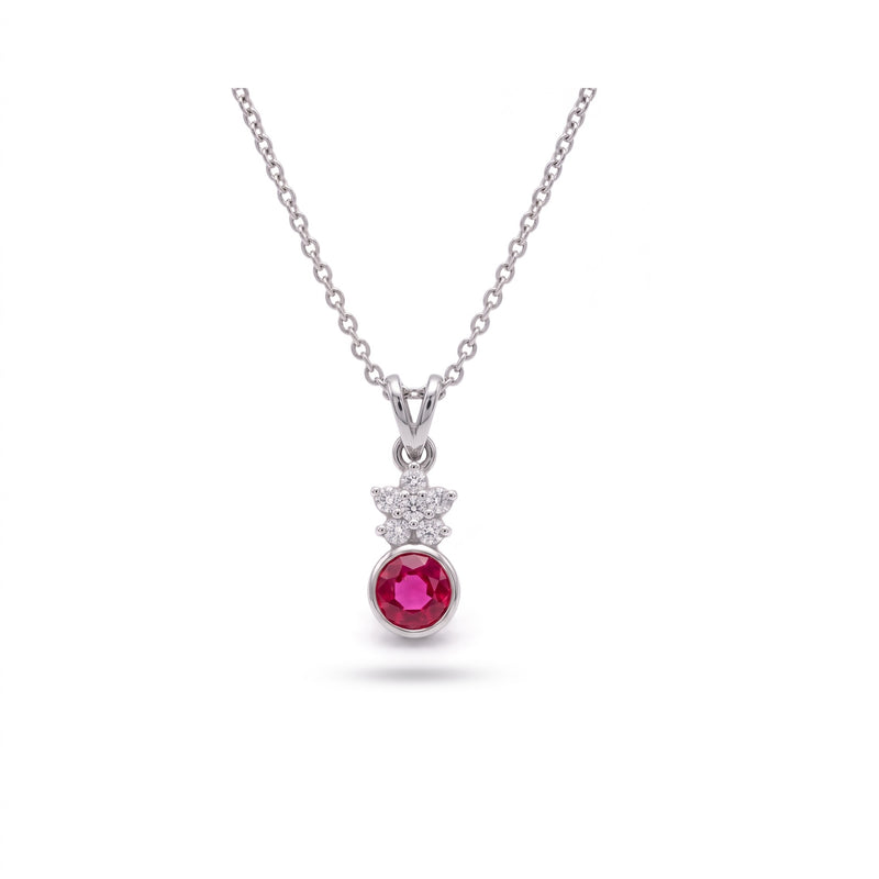 A silver pendant necklace featuring a round pinkish-red ruby gemstone and a small cluster of clear cubic zirconia stones, displayed on a clean white background.