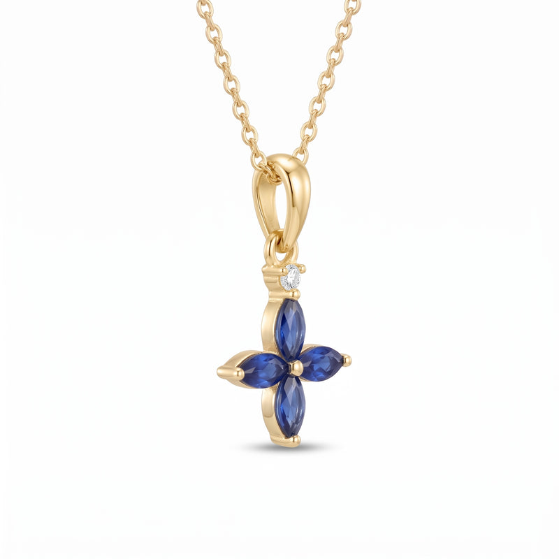 A yellow gold necklace with a flower-shaped pendant featuring four deep blue marquise-cut stones and a small clear accent stone, shown on a plain white background.