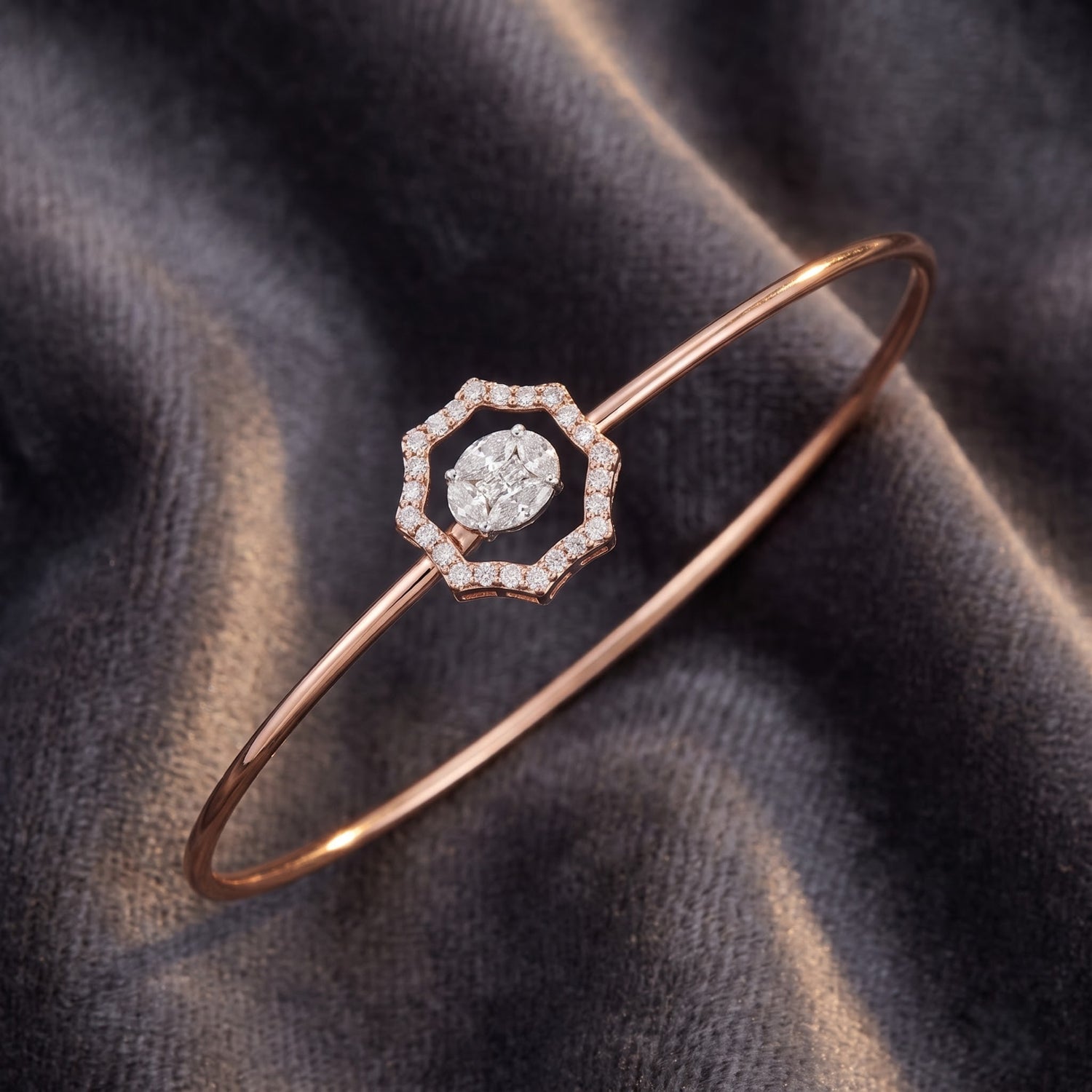 A rose gold bangle bracelet with a geometric octagonal center set with a halo of small clear stones and a central marquise-cut clear stone, displayed on a dark gray velvet fabric.