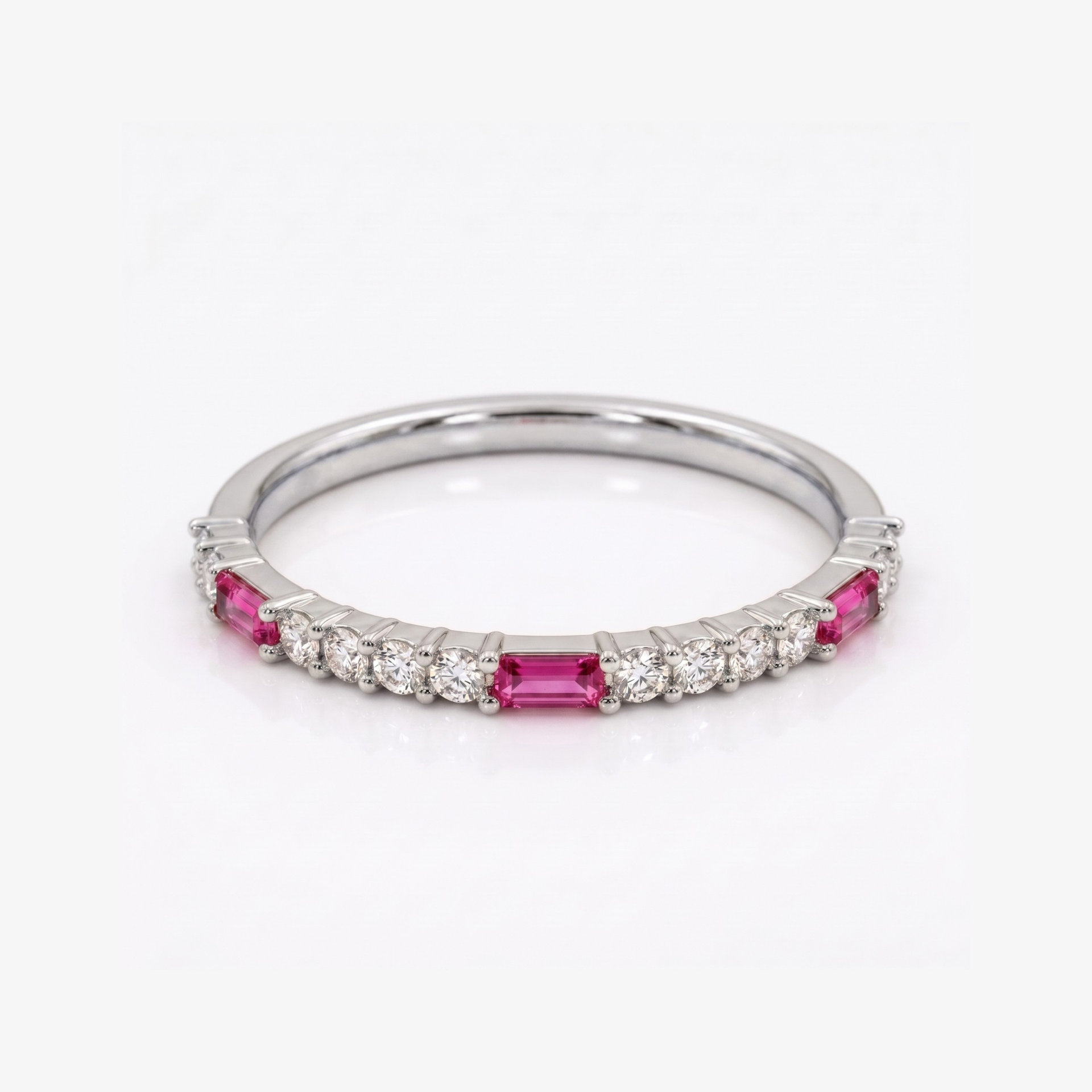 A silver band ring featuring rectangular pink gemstones and small round clear stones, photographed on a clean white background.