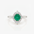 A silver ring featuring a round green emerald-cut center stone surrounded by a halo of round clear stones, set on a polished silver band against a white background.