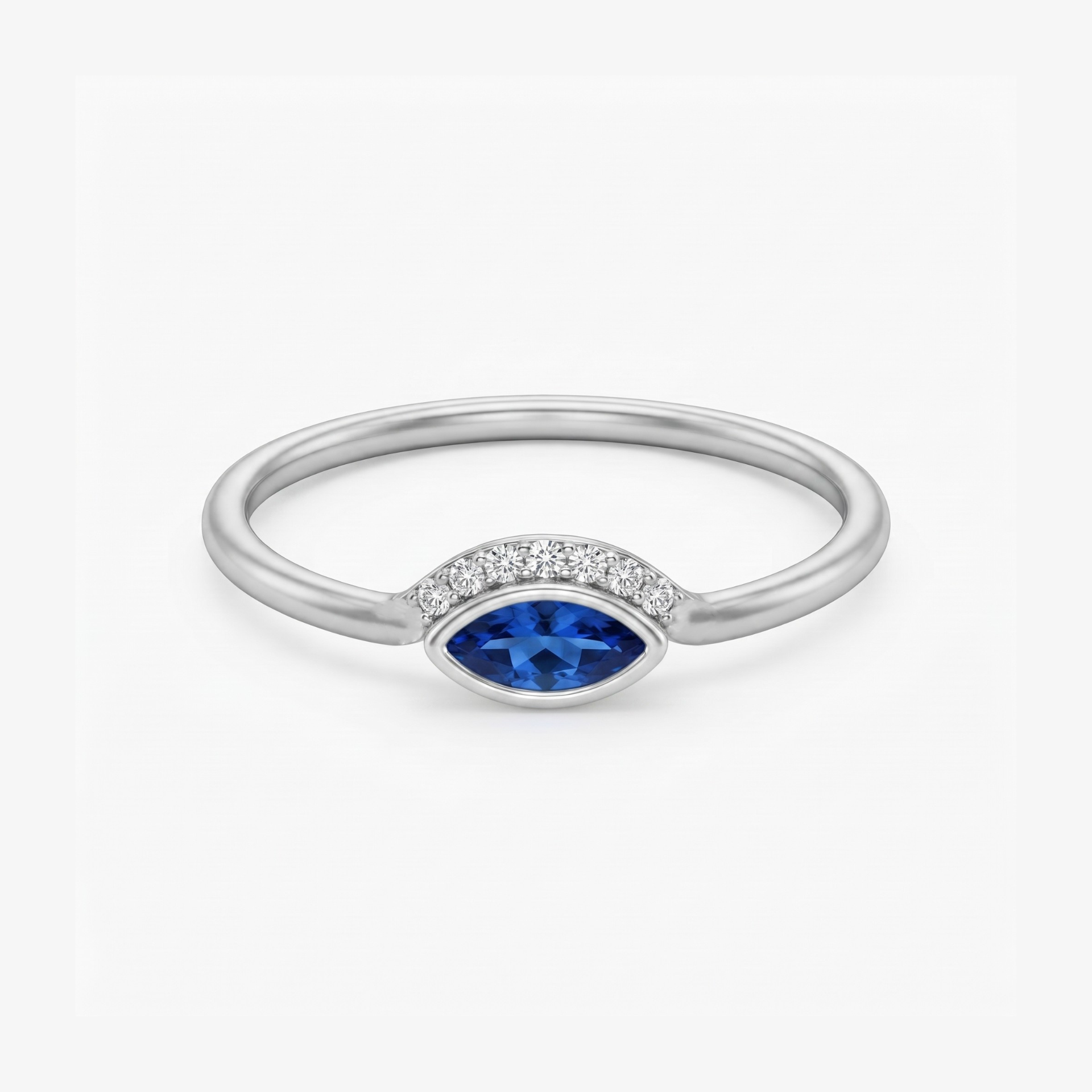 A silver ring featuring a marquise-cut blue gemstone in the center, flanked by a row of small clear stones on a clean white background.