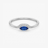 A silver ring featuring a marquise-cut blue gemstone in the center, flanked by a row of small clear stones on a clean white background.
