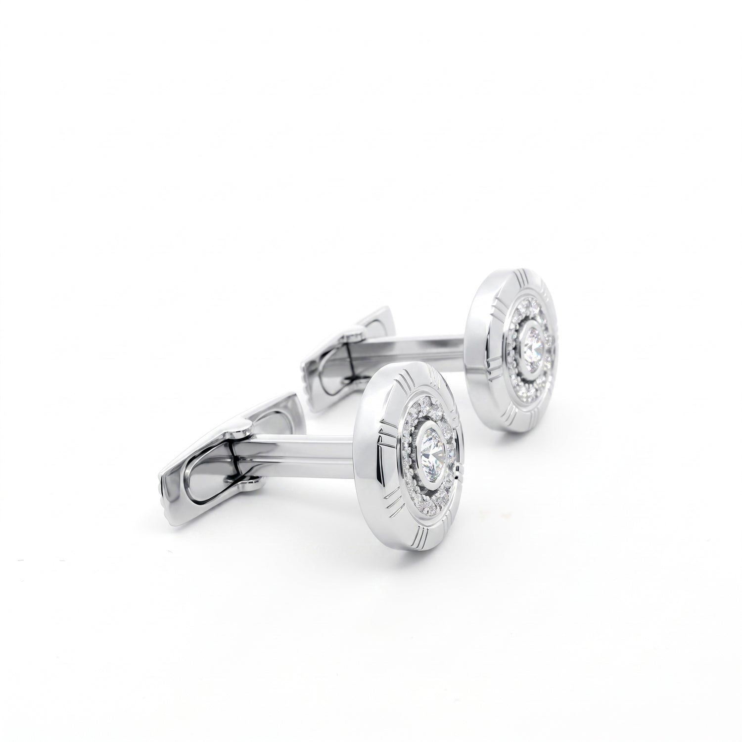 A pair of silver-toned round cufflinks with engraved outer rings and a clear central gemstone, displayed on a clean white background.