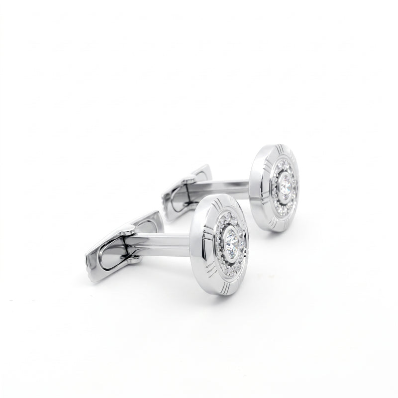 A pair of silver-toned round cufflinks with engraved outer rings and a clear central gemstone, displayed on a clean white background.