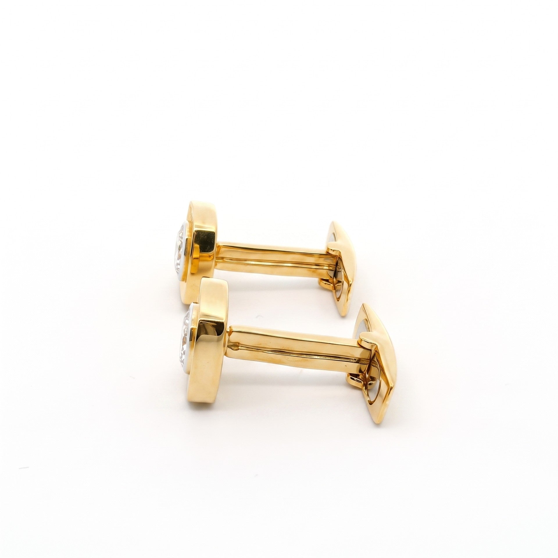A pair of gold cufflinks with round bezel-set clear gemstones, shown on a plain white background.