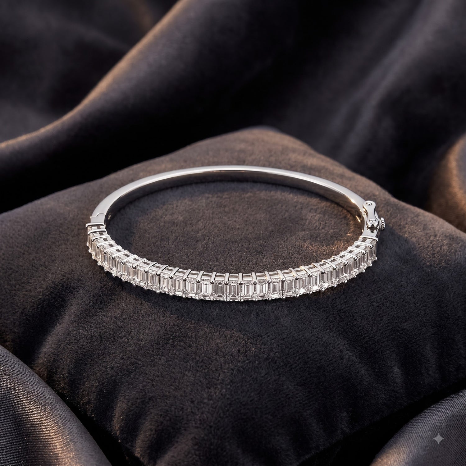 A silver-toned bangle bracelet with a continuous row of baguette-cut clear stones, displayed on a dark brown velvet cushion.