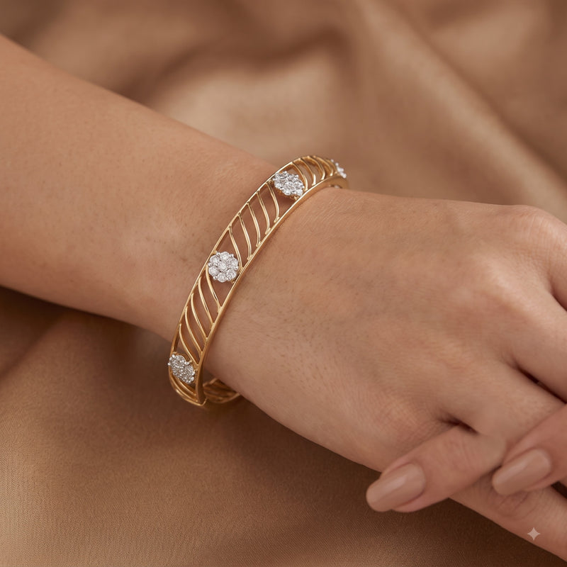 A gold bangle bracelet with three round-cut diamond accents, shown worn on a person&