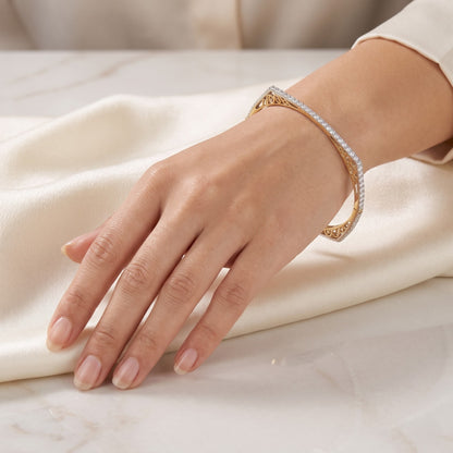 A gold bangle bracelet with pavé-set clear stones worn on a woman&