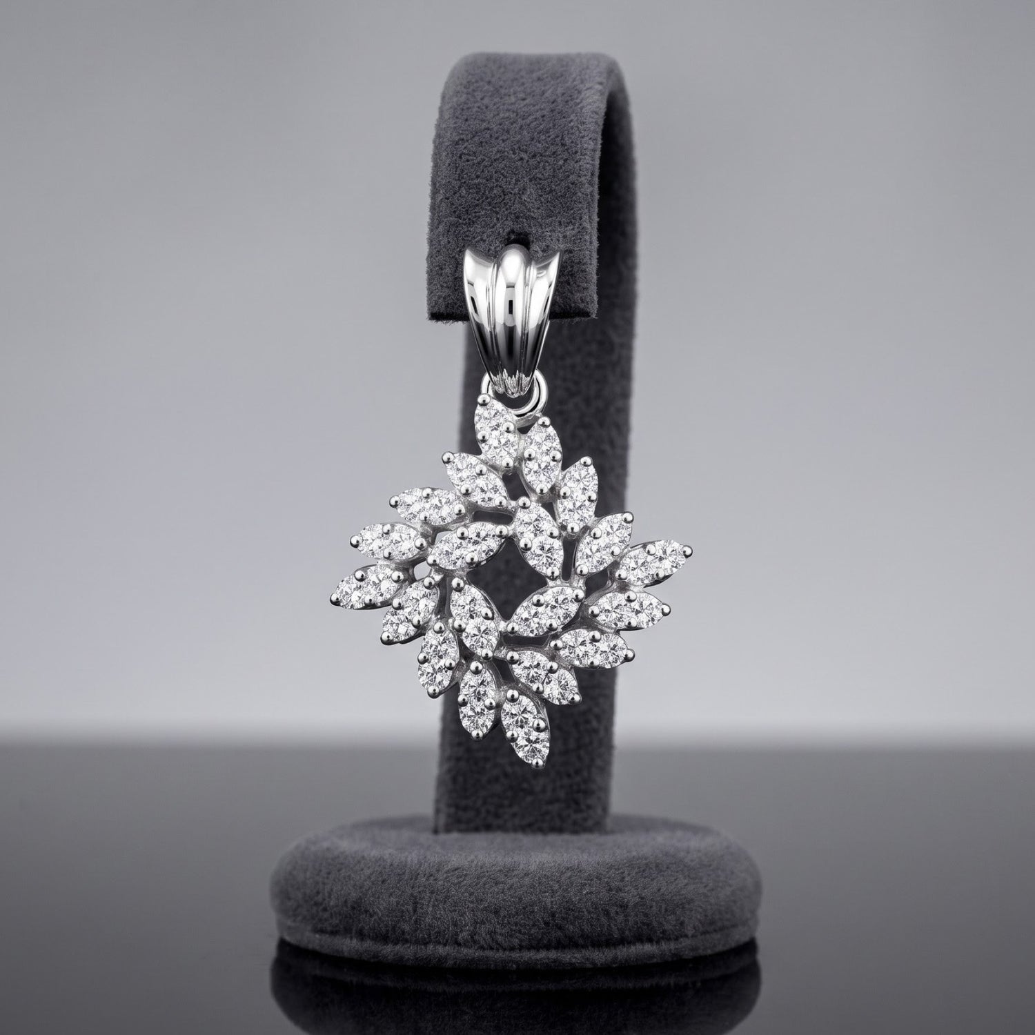 A silver snowflake-shaped pendant encrusted with clear stones, displayed on a dark gray velvet jewelry stand against a neutral gray background.