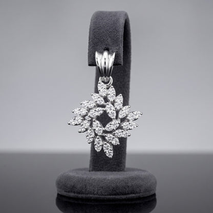 A silver snowflake-shaped pendant encrusted with clear stones, displayed on a dark gray velvet jewelry stand against a neutral gray background.