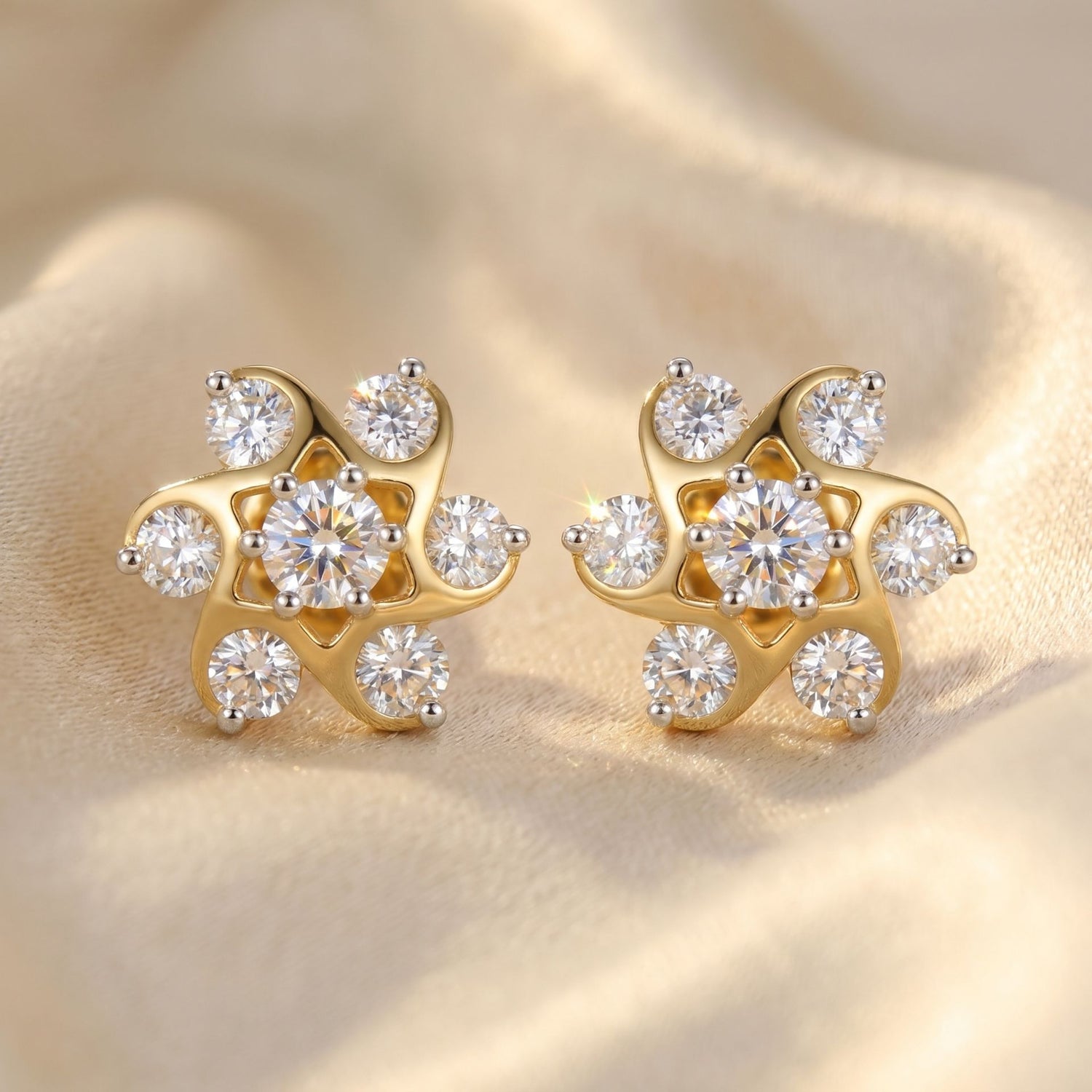 Gold earrings with diamond-like stones on a beige fabric background