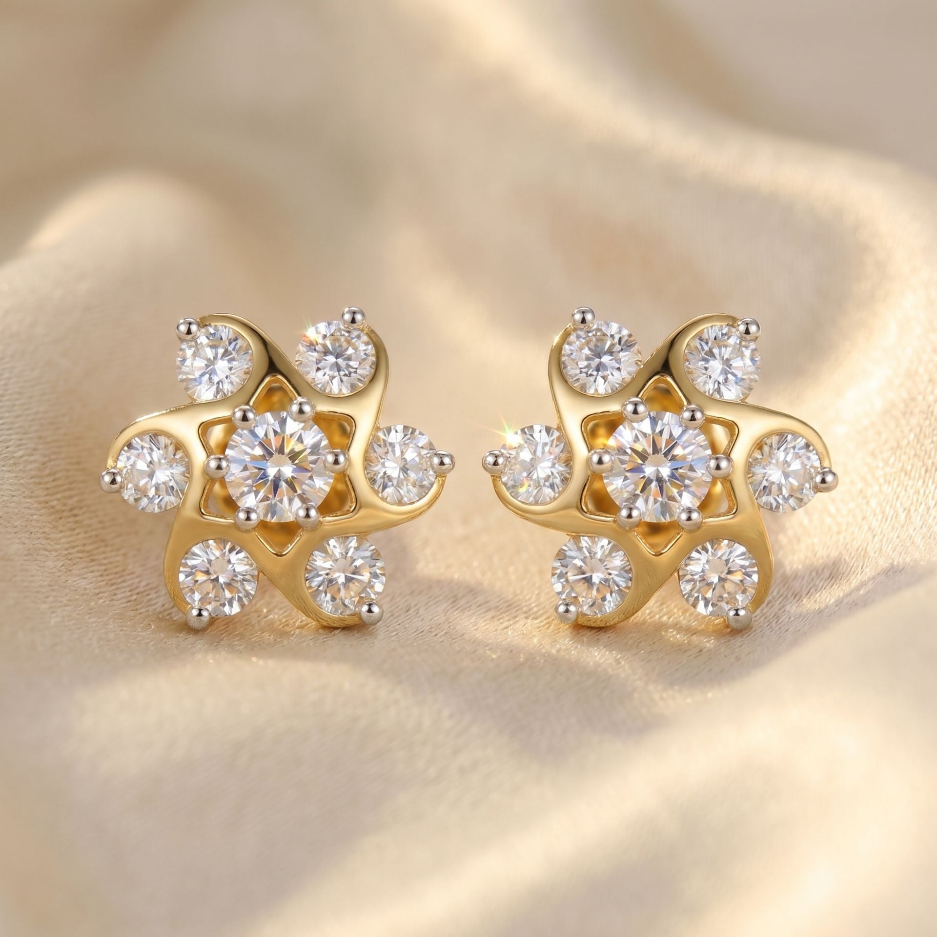 Gold earrings with diamond-like stones on a beige fabric background