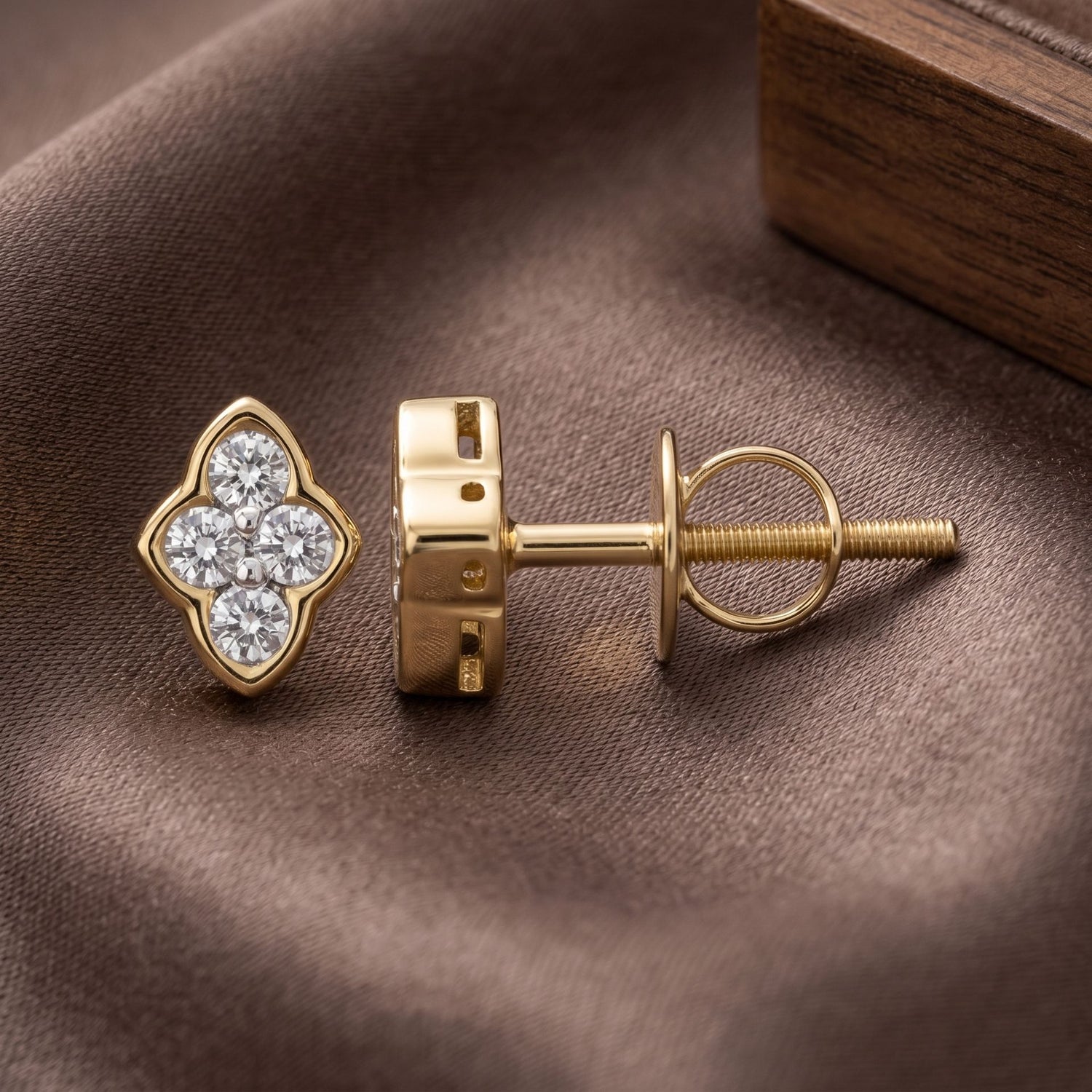 Gold earring with diamond clover design on a brown fabric background