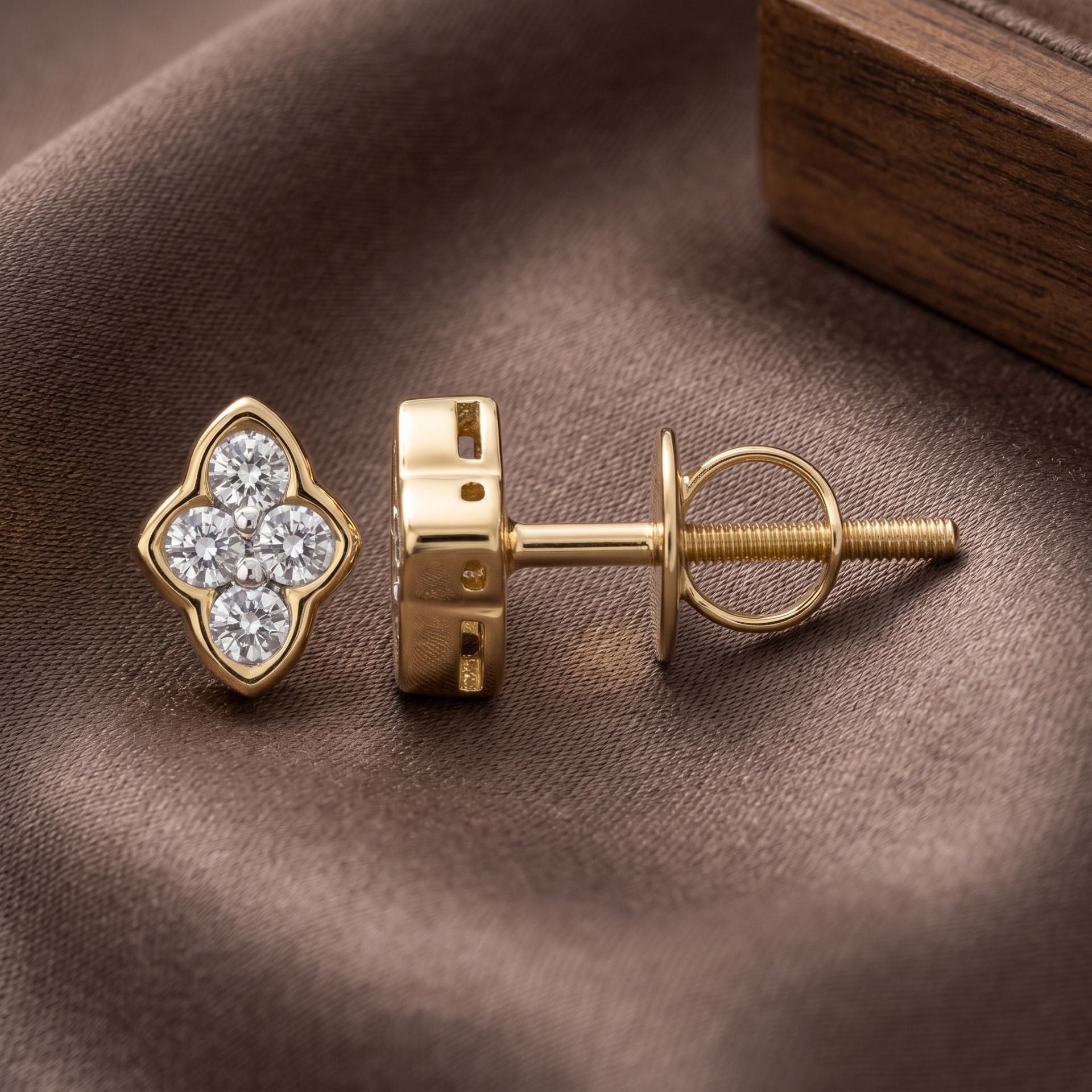 Gold earring with diamond clover design on a brown fabric background