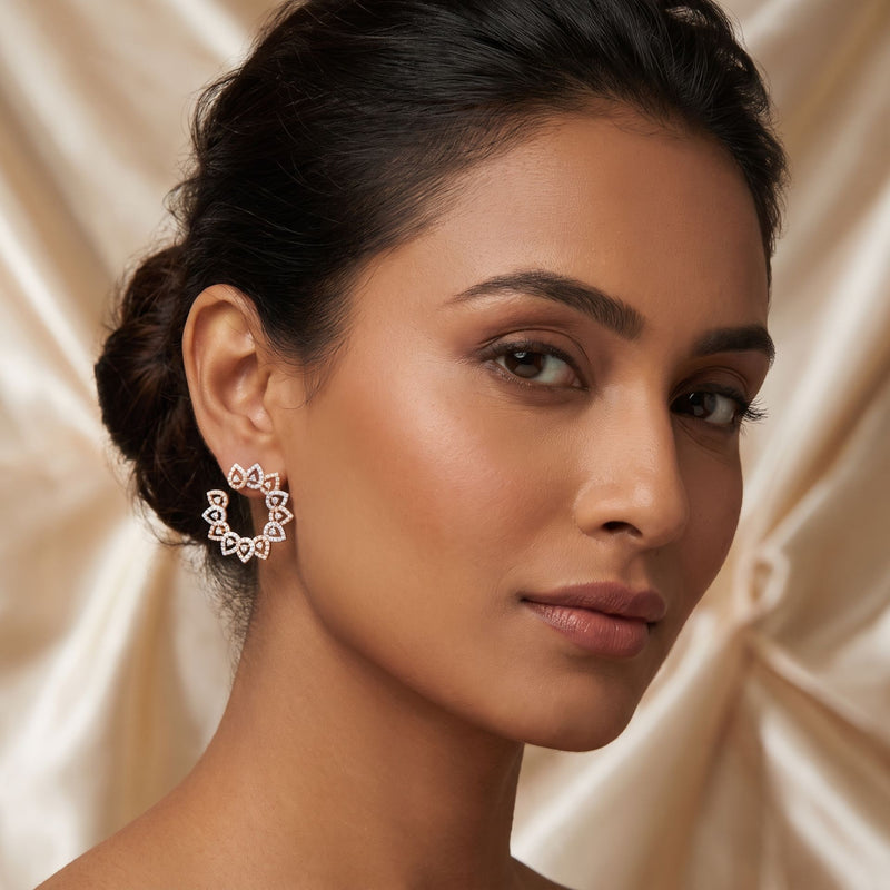 Woman wearing a pair of hoop earrings against a beige fabric background