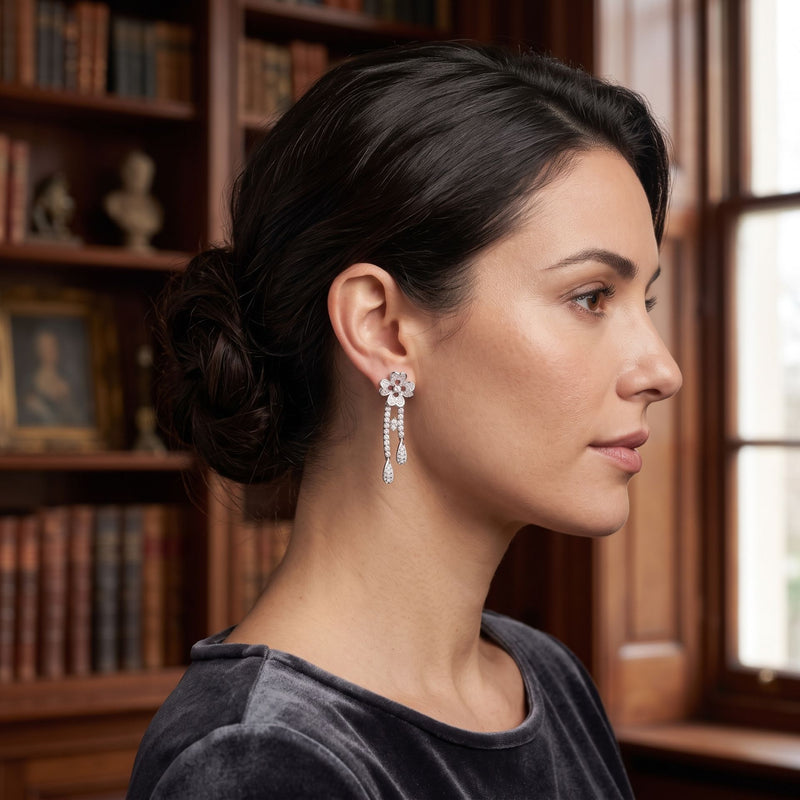 Woman wearing earrings with a bookshelf and window in the background