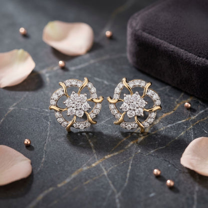 Gold and diamond earrings on a dark surface with petals and a box.