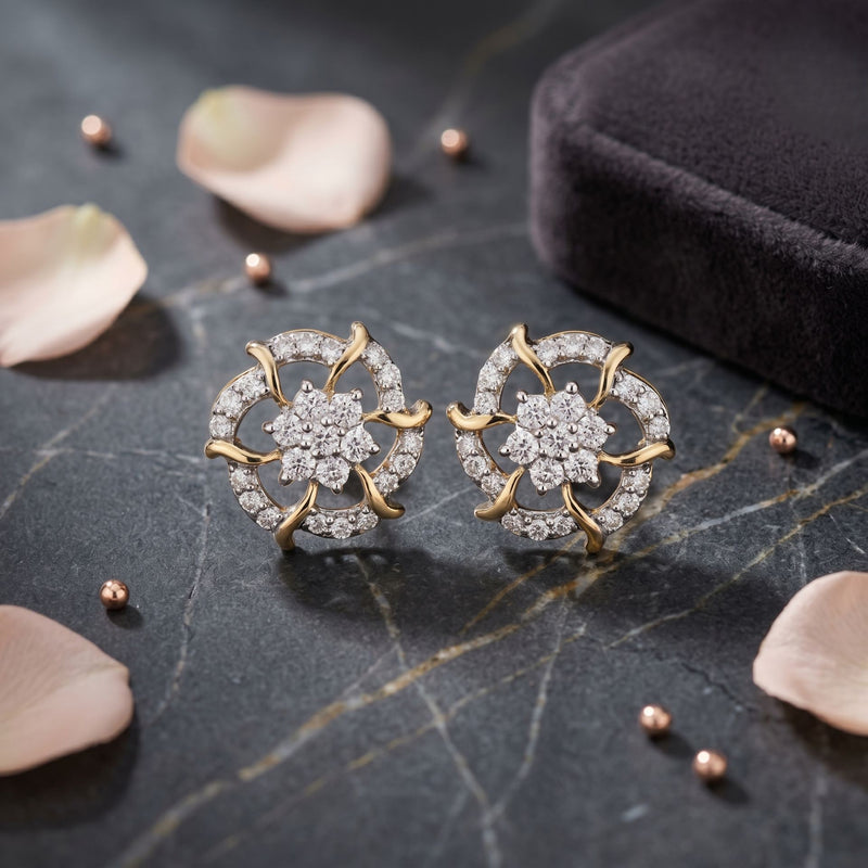 Gold and diamond earrings on a dark surface with petals and a box.