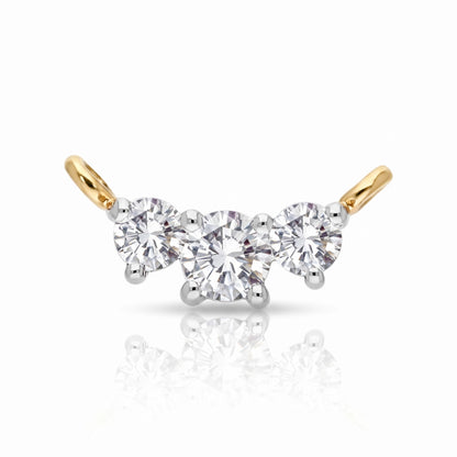 A three-stone diamond engagement ring featuring a central round brilliant-cut diamond flanked by two smaller round diamonds, set in a yellow gold and white gold or platinum bridge with curved gold posts.