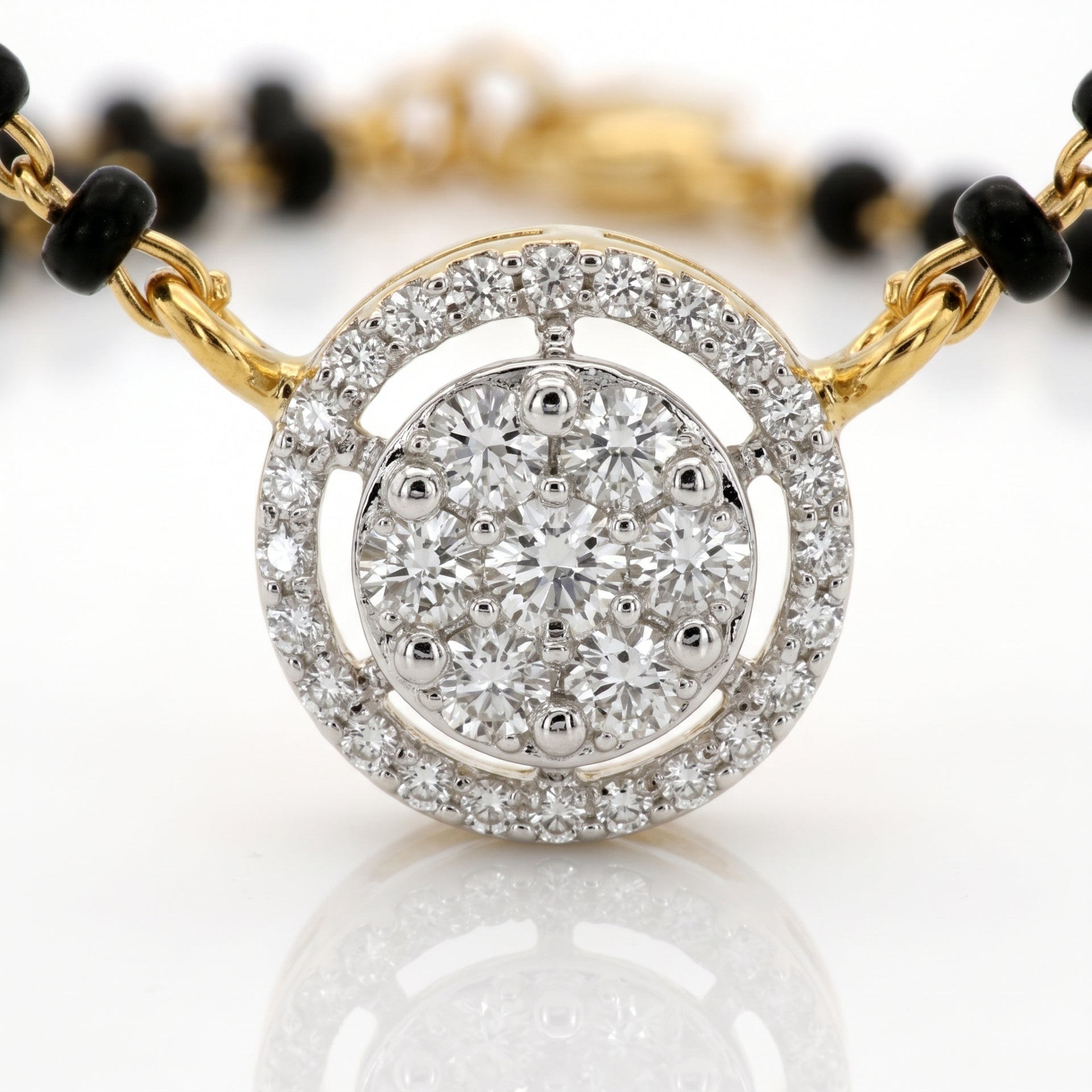 A close-up of a round diamond pendant bracelet featuring a central cluster of round diamonds surrounded by a double halo of smaller diamonds, set in yellow gold and white gold, with a black beaded chain extending from the sides.