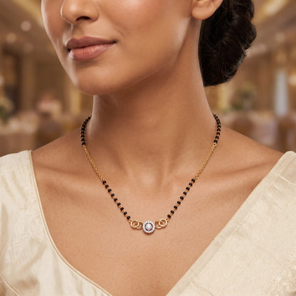 A close-up lifestyle shot of a woman wearing a traditional Indian black bead necklace with a gold chain, a central round white stone, and decorative gold rings.