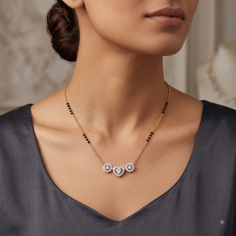 A close-up lifestyle shot of a model wearing a delicate gold necklace with three interlocking heart pendants, accented with small black beads on the chain.