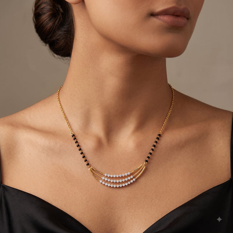 A close-up of a model wearing a delicate gold necklace with three curved rows of white pearls and small black bead accents.