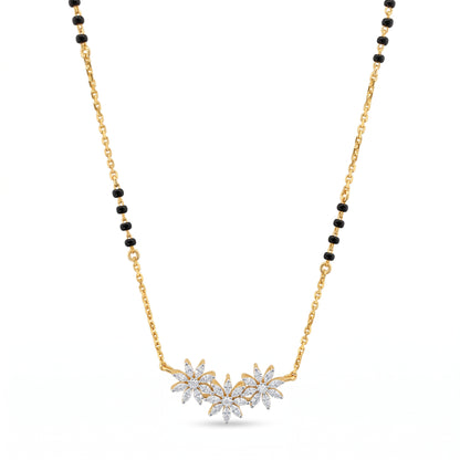 A gold chain necklace with a black bead accent and a central cluster of three flower pendants set with clear stones, shown on a plain white background.