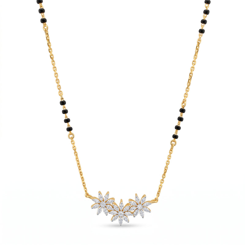 A gold chain necklace with a black bead accent and a central cluster of three flower pendants set with clear stones, shown on a plain white background.