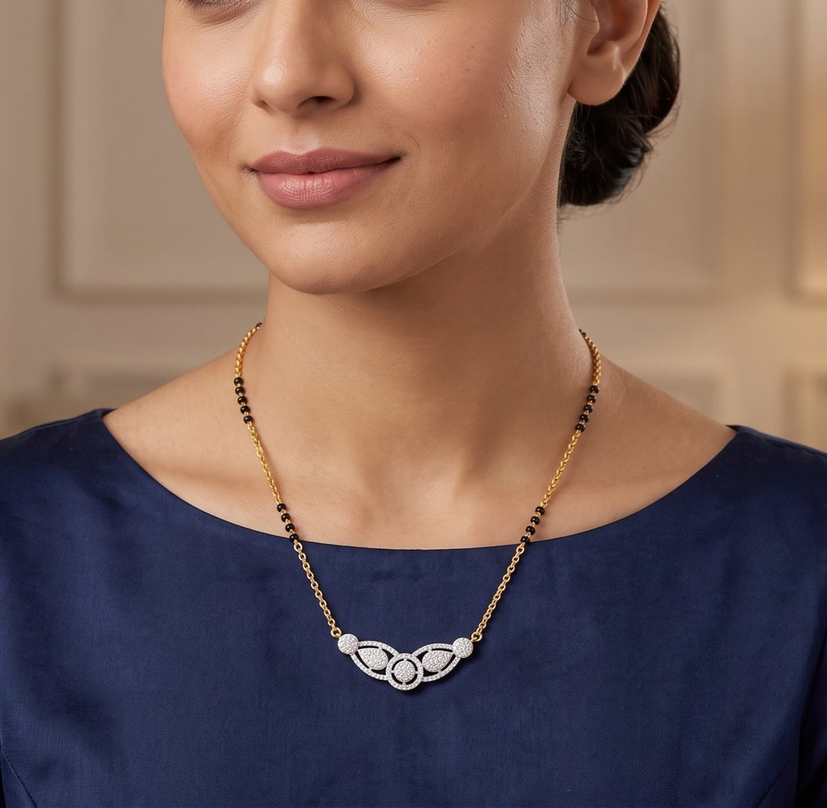 A close-up of a woman wearing a delicate gold necklace with a white and black beaded pendant, paired with a navy blue satin top.