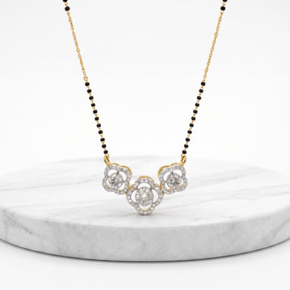 A delicate gold and black beaded necklace with a central cluster of clear gemstones, displayed on a round white marble pedestal against a clean white background.