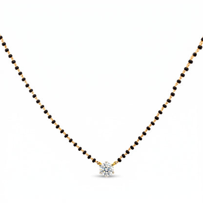 A delicate black and gold beaded necklace with a small, clear, multi-stone starburst pendant, displayed on a solid white background.