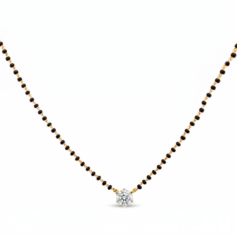 A delicate black and gold beaded necklace with a small, clear, multi-stone starburst pendant, displayed on a solid white background.
