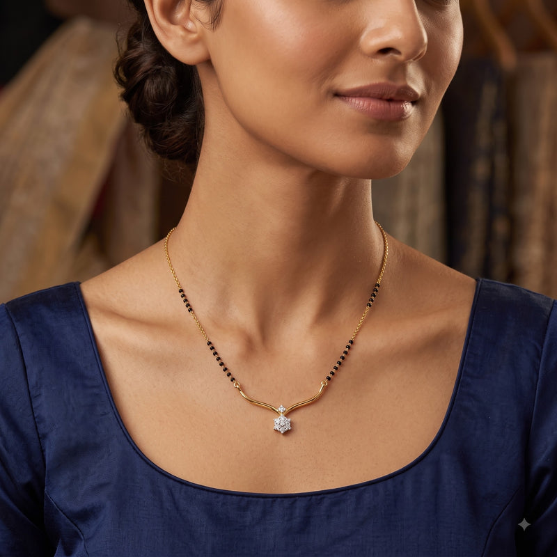 A close-up lifestyle shot of a woman wearing a delicate gold necklace with a star-shaped pendant and small black bead accents, paired with a navy blue top.